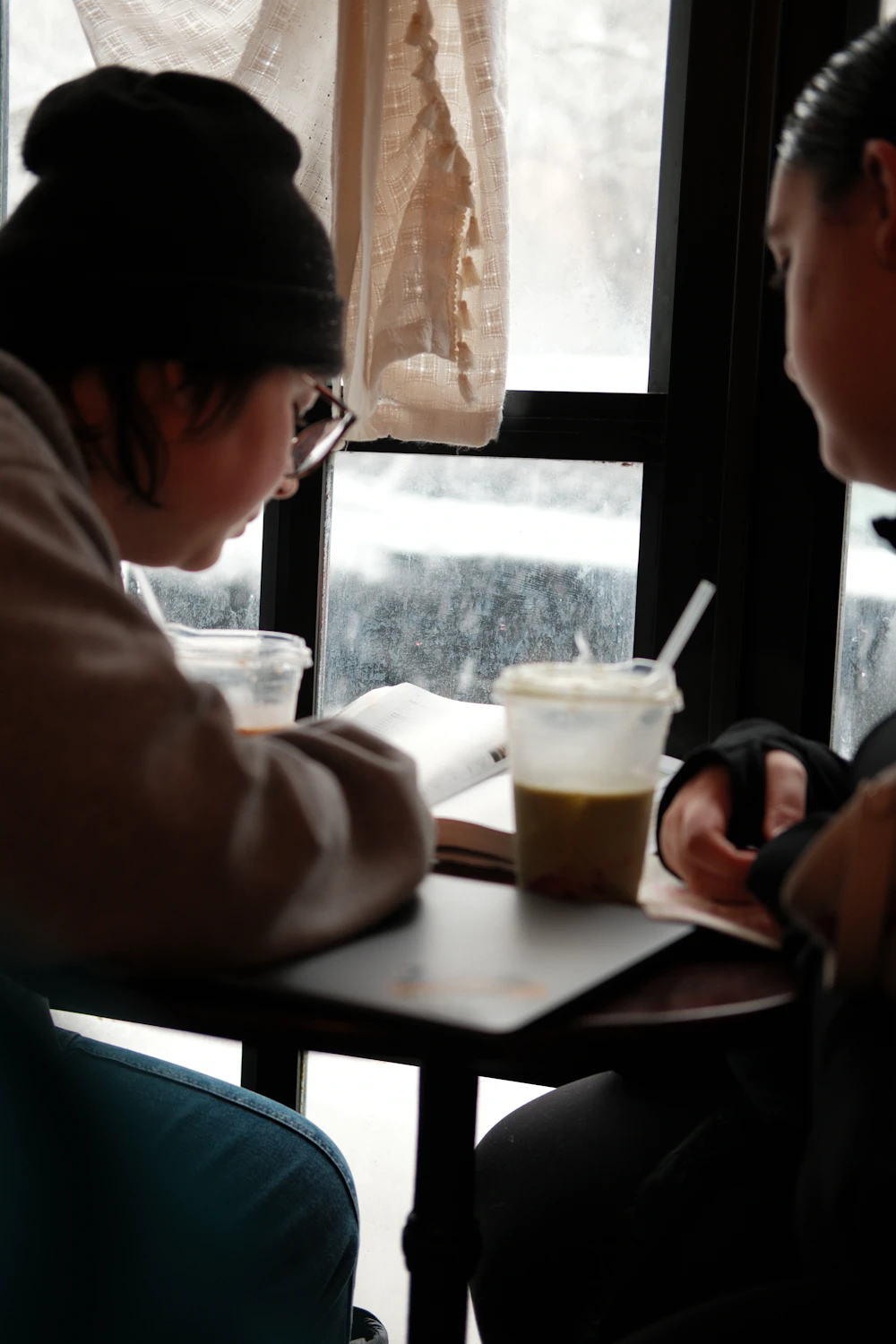 Two friends reading at a coffee shop table